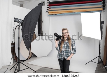 Happy girl professional photographer in photo studio with digital SLR camera in hands
