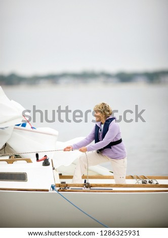 Mature adult woman winching a sail while on a boat.