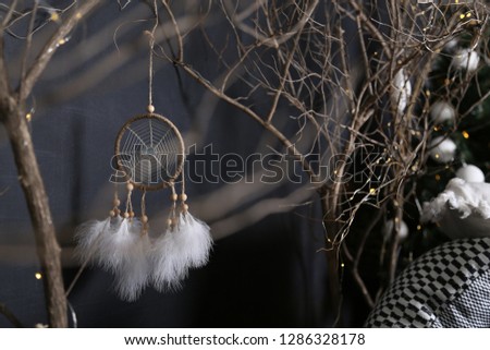 wooden branches and Dreamcatcher with white feathers. dark background and black-and-white pillows.