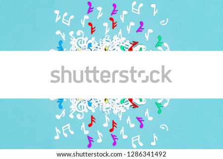 Musical confetti cloud and rain on blue background, close up. Musical symbols creative minimalistic background, flat lay. Falling Musical Notes as rain.Music frame with note confetti, copy space