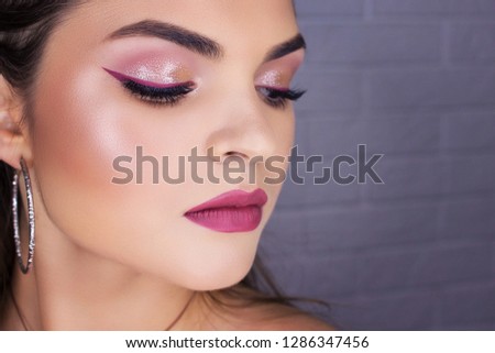Glamour close-up portrait of beautiful woman model face with winged bright blue eyeliner make-up, clean skin on white background Royalty-Free Stock Photo #1286347456