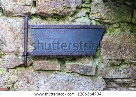 Old metal signpost on a ruined stone castle wall, medieval sign, mockup