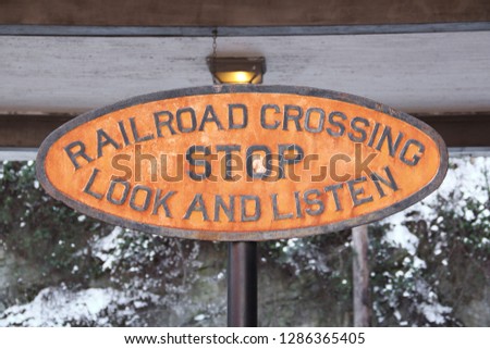 Detail of an old, weather worn sign posted near the Amtrak station platform in Staunton, VA. The sign reads "RAILROAD CROSSING / STOP / LOOK AND LISTEN."