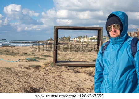 Hooded  unhappy men in sunglasses standing on the sandy beach near rescue booth thinking and looking to the ocean coast and sun