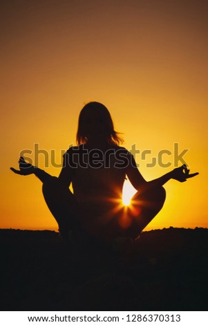 Girl sitting in a yoga pose at sunset. Silhouette