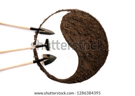 Garden tools - shovel, rake on the background of a circle of soil. Yin and Yang symbol on a white background. Crop production, tools, gardening concept.
