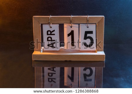 Wooden calendar with date 15th of April on dark