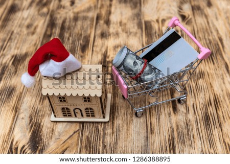 Dollars in cart and house model with santa hat