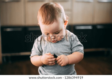 the child holds a black lighter and tries to light