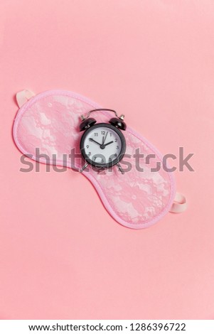 Sleeping eye mask, alarm clock isolated on pink pastel colourful trendy background. Do not disturb me, let me sleep. Rest, good night, siesta, insomnia, relaxation, tired, travel concept