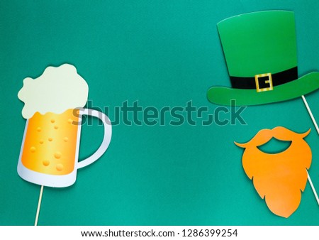 Creative st Patricks Day green background. Flat lay composition of Irish holiday celebration with photo booth decor: hat, beer, beard. With Copy space, greeting card, top view