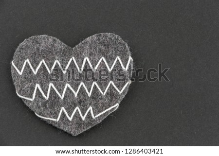 Valentines day background with beautiful handmade toy hearts lying on black cardboard. Love, romance concept. Felt hearts with geometric zig zag embroidered lines. Stylish chevron pattern. Copy space.