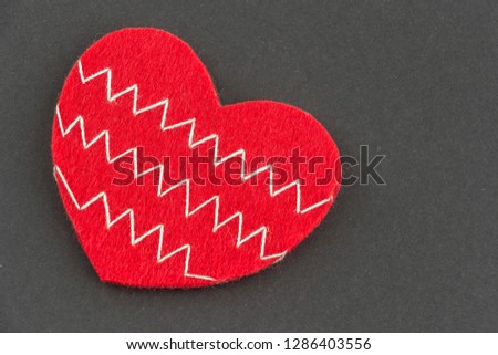 Valentines day background with beautiful handmade toy hearts lying on black cardboard. Love, romance concept. Felt hearts with geometric zig zag embroidered lines. Stylish chevron pattern. Copy space.