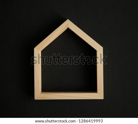 Wooden frame in the shape of a house on black background