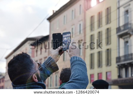 Hipster man photographing with smartphone in an Italian art city. Bologna, Italy