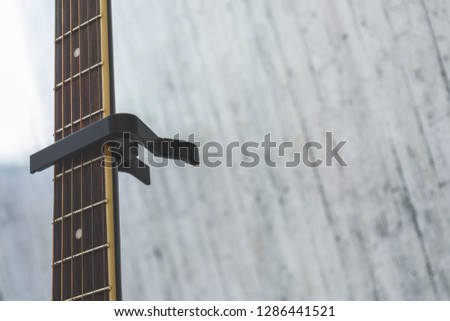 black capo mounted on the neck of an acoustic guitar