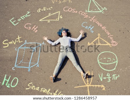 schoolgirl laying on a asphalt with chalk drawn mathenatics formulas and geometric figures