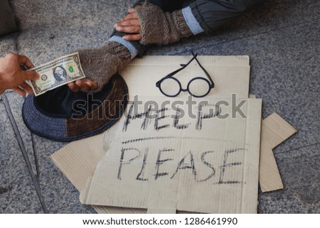 Homeless man is lie down on walkway in town.He is receive dollar.He is  hoping to have the better life. poverty,despair, Photo Sympathetic and hope concept.