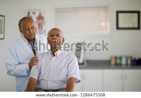 Senior man having his heartbeat listened to by a male doctor inside an office. Royalty-Free Stock Photo #1286475508