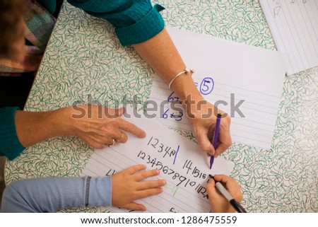 Mature woman helping a young boy with math.