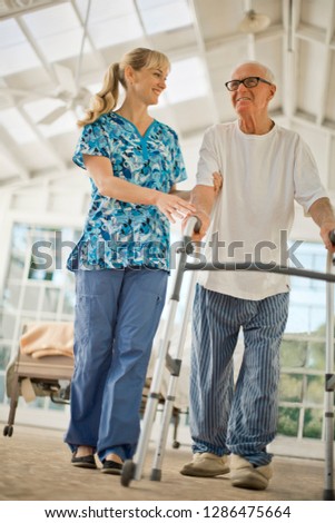 Happy young nurse comforting a senior man.