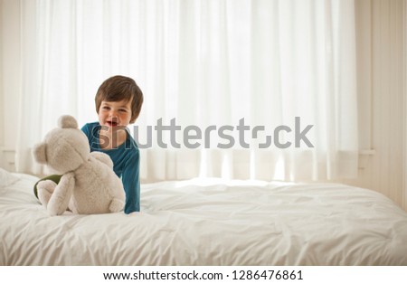 Young boy playing on a bed inside a bedroom.