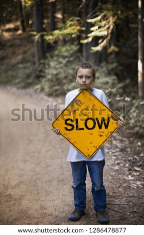 Boy holding slow sign on dirt road