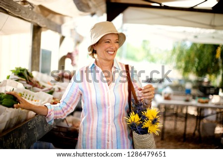 Smiling woman shopping at a farmer's market.