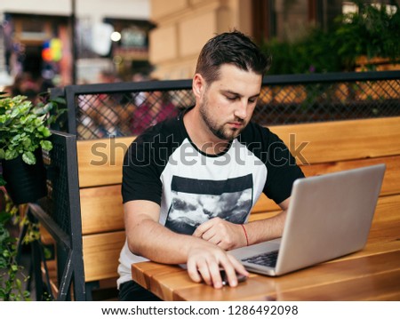 Young man in street cafe with laptop and smartphone