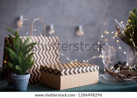gift box and a package are on a serving green table, a craft box with zigzags on the lid, a style package of the same, room, grey background
