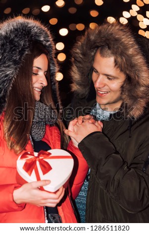 Attractive couple in love hugging and enjoying an intimate moment together, against the backdrop of city lights - Image