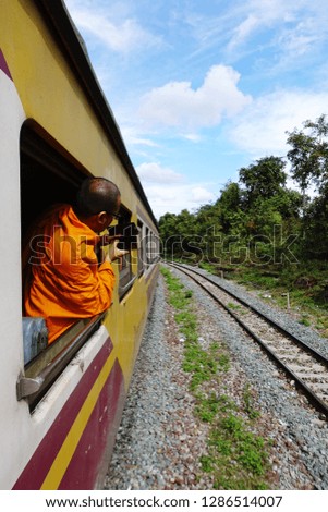 Buddhist monk leans out of moving train and taking pictures with his mobile phone