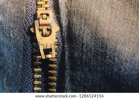 Macro of yellow zipper on blue jeans trousers, selective focus zipper. Royalty high-quality free stock photo image of close up of gold zipper on a blue jean trousers background with space for text