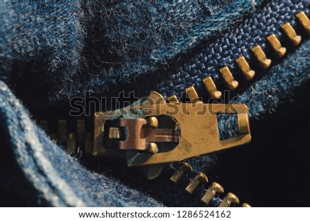 Macro of yellow zipper on blue jeans trousers, selective focus zipper. Royalty high-quality free stock photo image of close up of gold zipper on a blue jean trousers background with space for text