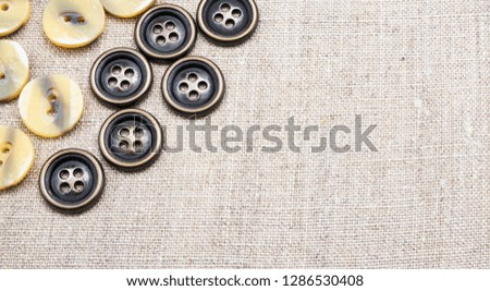 Metal and mother of pearl buttons sewn on natural linen fabric