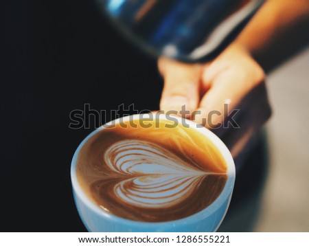 Close up barista hands pouring milk in coffee cup for making latte art.