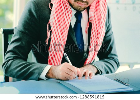 Arabian businessman working in modern office. Successful Arabian business person signing a contract, working in office. Businessman signs a contract. man contract signing hand writing concept.
