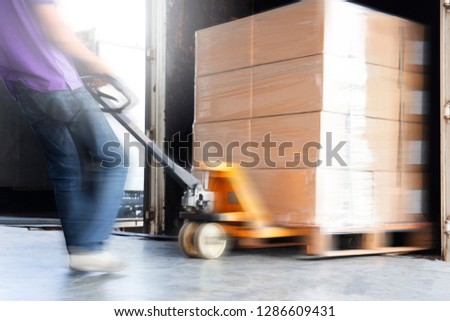 warehouse worker are dragging hand pallet truck or manual forklift with the shipment pallet unloading into a truck.
