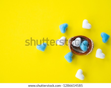 A lot of blue hearts shape and white hearts shape and two heart shape in small basket put on yellow background, image using for valentine ‘s day signs and lovely sweet concept