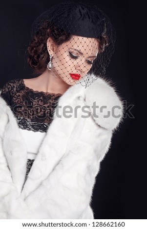 Elegant woman wearing in white fur coat isolated on black background