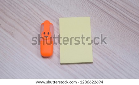 yellow note and orange highlighter on wood background.