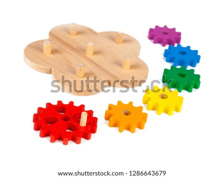 Photo of a wooden toy  children's sorter with small wooden details in the form of gears, in different colors  on a white isolated background. The toy for the development of fine motor child