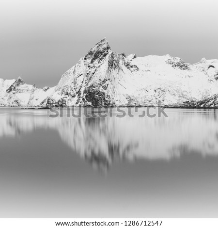 Panoramic landscape, winter mountains and fjord reflection in water. Norway, the Lofoten Islands. Black and white photography above the arctic circle.