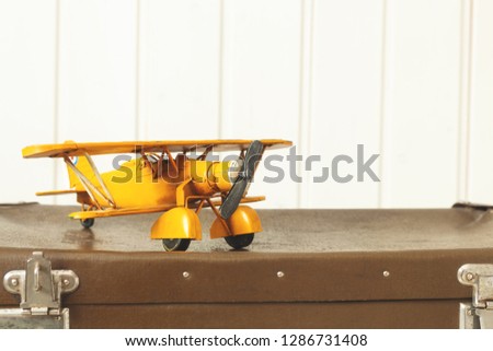 Toy yellow metal plane Old retro suitcases White wooden background Vintage tinting Copy space