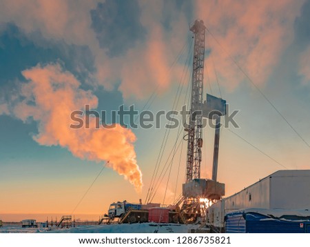 Drilling a deep well with a drilling rig in an oil and gas field. The field is located in the Far North beyond the Arctic Circle. Beautiful dramatic sky of the polar day. Royalty-Free Stock Photo #1286735821