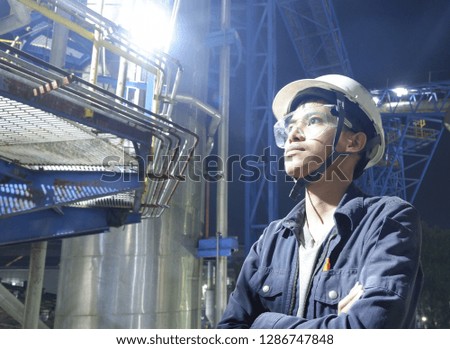 Asian young men Checking the machine inside the factory, industrial equipment, electrical equipment at night.