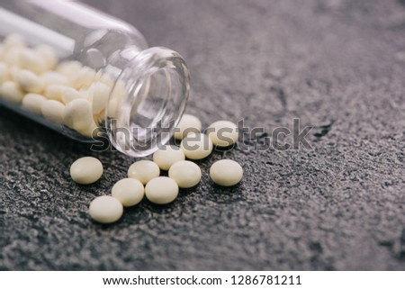 selective focus of scattered white pills from bottle on grey surface