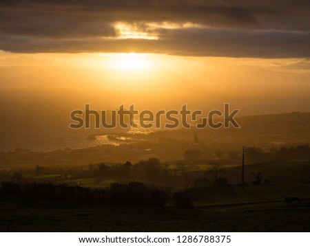 Aerial view of Vila Franca do Campo town volcanic islet during orange sunset with clouds, contre-jour light, Sao Miguel Island, Azores, Portugal