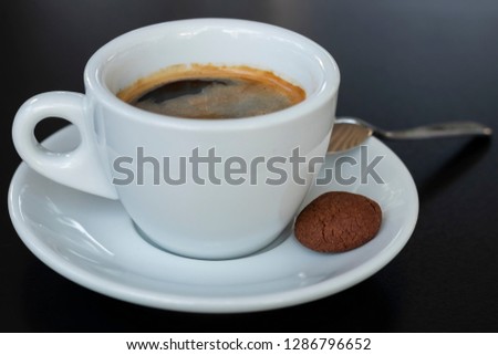 Cup of espresso coffee, teaspoon and a cookie