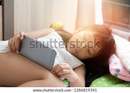 Cute little girl watching cartoons on mobile phone,Preschool kid sitting while serious face playing games on smart phone,Child typing or using cell phone while relaxing at home..
